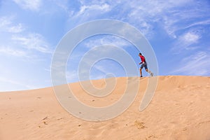 Man runs up the dune in the Wadi Araba desert, Jordan
