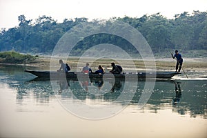 Man runs a wooden boat on the river, Nepal, Chitwan National Park,