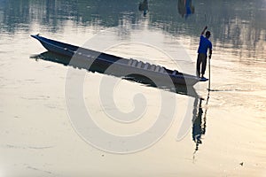 Man runs a wooden boat on the river, Nepal, Chitwan National Park,