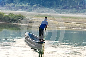 Man runs a wooden boat on the river, Nepal, Chitwan National Park,