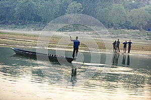 Man runs a wooden boat on the river, Nepal, Chitwan National Park,