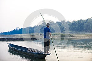 Man runs a wooden boat on the river, Nepal, Chitwan National Park,