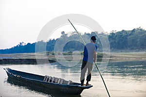 Man runs a wooden boat on the river, Nepal, Chitwan National Park,