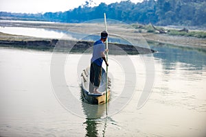 Man runs a wooden boat on the river, Nepal, Chitwan National Park,