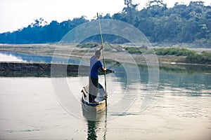 Man runs a wooden boat on the river, Nepal, Chitwan National Park,