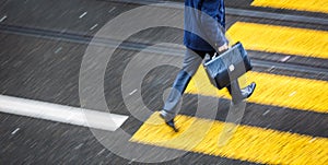 Man rushing over a road crossing in a city on a rainy day photo