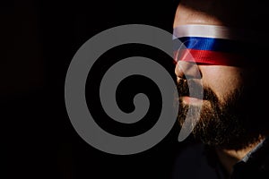 Man with Russian flag blindfold on black background, Russian propaganda closed people& x27;s eyes concept. photo