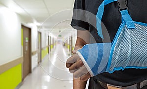 Man`s arm in cast and sling with blurred hospital background