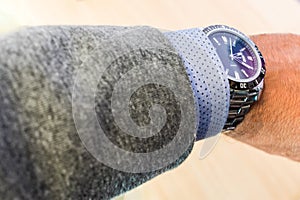 Man`s arm showing steel watch with shirt and jacket