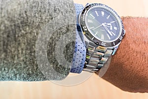 Man`s arm showing steel watch with shirt and jacket