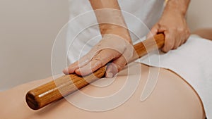 Man`s back during traditional thai massage with stick. Oriental alternative medicine with wooden tools. Body care and SPA in