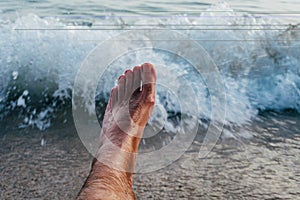 Man`s bare foot in front of the sea waves