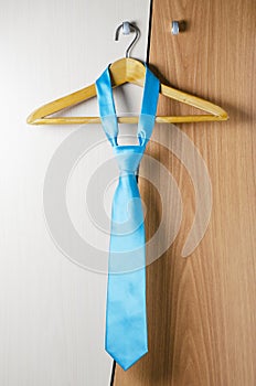 A man`s blue tie hangs on the door of the chiffonier. The concept of a successful man`s style photo