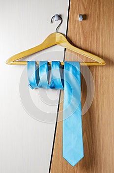 A man`s blue tie hangs on the door of the chiffonier. The concept of a successful man`s style photo