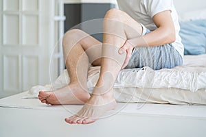 The man's calf muscle cramped, massage of male leg at home