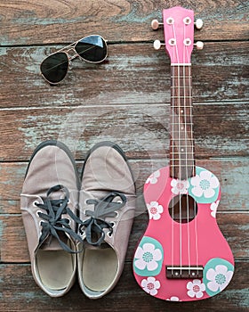 Man's clothing, sunglasses, and shoes lay on wood vintage background,