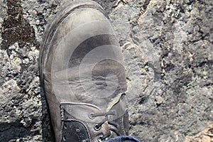 Man`s construction boot resting on a rocky surface.