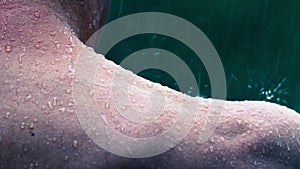 A man`s drenched shoulders flex while getting pelted from rain in a thunderstorm