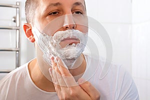 Man& x27;s face applying facial foam, close-up. Shaving cream, skin care
