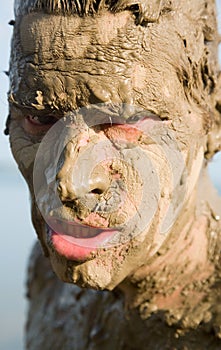 Man's face is very dirty in the mud