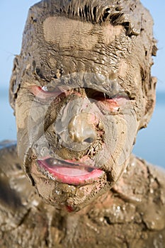 Man's face is very dirty in the mud