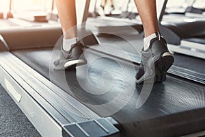 Man`s feet on treadmill in fitness club, healthy lifestyle
