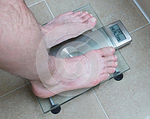 Man& x27;s feet on weight scale - Eat healthy