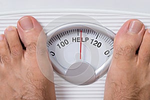 Man's feet on weight scale indicating help