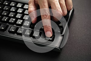 Man`s finger pressing Escape key on black computer keyboard