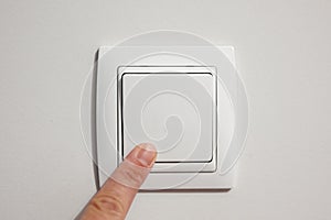 A man`s finger turning a wall switch on or off