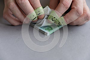 A man`s fingers are counting the money. A wad of euro bills. The index and middle fingers of both hands are wrapped in green tape