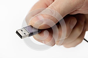 Man`s fingers are holding a USB connector, white background.