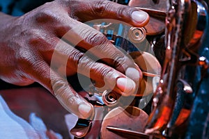 Man`s fingers press keys on his saxophone, playing live jazz, extreme closeup of a virtuoso`s hand