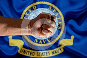A man`s fist on the background of the U.S. Navy flag. A firmly clenched fist symbolizes the strength and power of the army, the