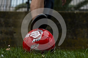 A man& x27;s foot in a sneaker on a soccer ball on green grass.