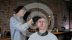 Man's hair cutting by barbers scissors and comb with barbershop logo behind in slow motion. Mans hands making male