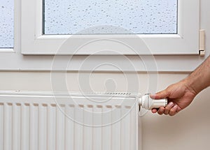 Man's hand adjusting the temperature of a radiator