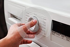 Man`s hand adjusting washing machine