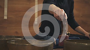 Man`s hand beats the Tibetan singing bowls