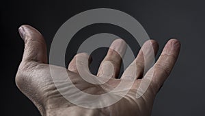 Man`s Hand Begs For Something On A Dark Background. Open Man`s Cupped Hand Begging For Alms On Gray Background. High Quality Pho