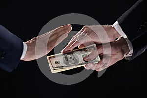 A man& x27;s hand in a black suit holds out a wad of money, which refuses. World Anti-Corruption Day concept