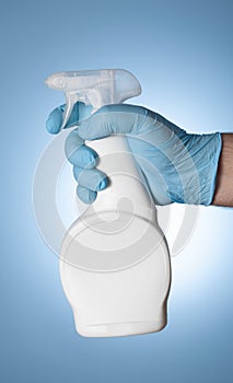 A man`s hand in a blue medical glove holds a white plastic spray gun from covid-19