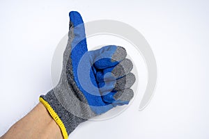 a man& x27;s hand in blue rubberized work gloves shows a thumbs up on a blue background