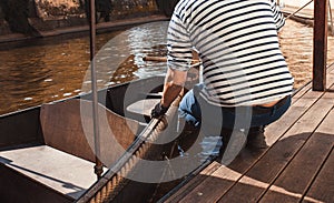 Man s hand with boat tiying rope. Sailor seaman gondolier Yachtsman moors his motor boat at jetty. Close up hands and bow of the b