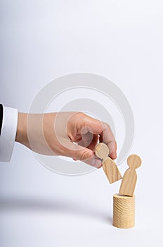 The man`s hand of a businessman in a business suit holds a wooden figure of a man in his hand and moves another figure