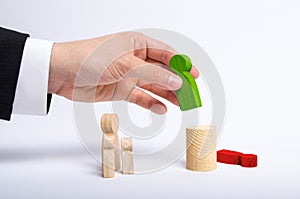 The man`s hand of a businessman in a business suit holds a wooden figure of a man in his hand and moves another figure