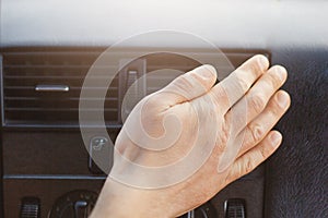 Man`s hand on car heater or conditioner, regulates temperature in automobile while drives. Car`s accessories or panel. Conditionin