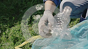 a man's hand collects plastic bottles from the ground into a trash bag, eco, keep the green planet clean, problem of