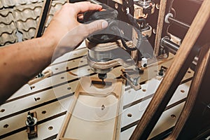 Man`s hand at the computer numerical control machine for wooden tools. CNC equipment for maintenance control and details