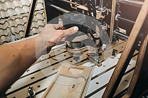 Man`s hand at the computer numerical control machine for wooden tools. CNC equipment for maintenance control and details